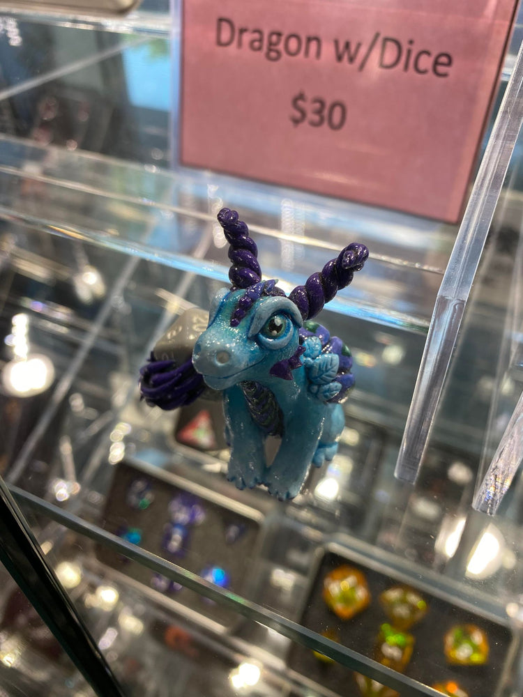 Image shows blue and purple dragon holding a gray d20.